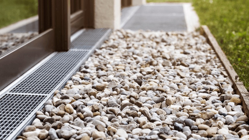 Exterior foundation drainage system with gravel bed and steel grates
