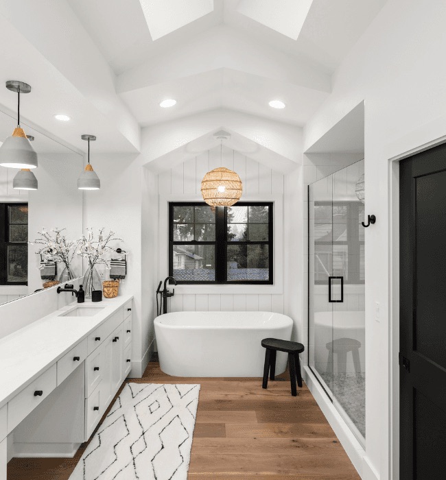 Fully renovated bathroom with freestanding tub, skylights, and wood floors