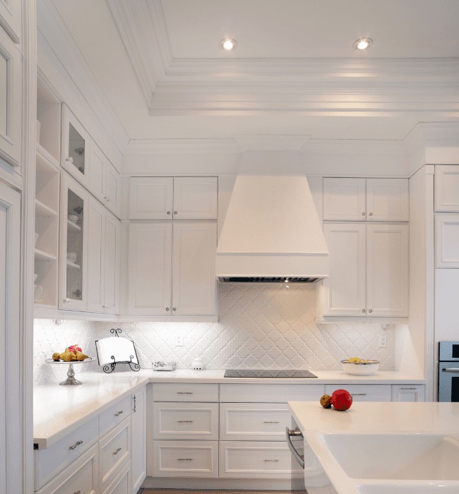 Bright white kitchen remodel with custom cabinetry, tiled backsplash, and detailed crown molding