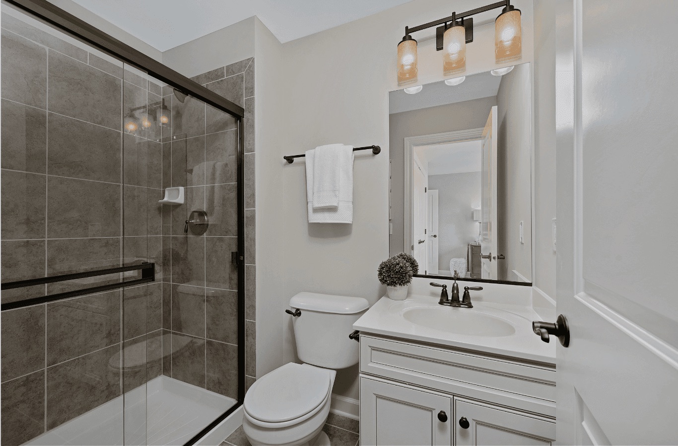 Small bathroom remodel with tiled shower, white vanity, and bronze fixtures